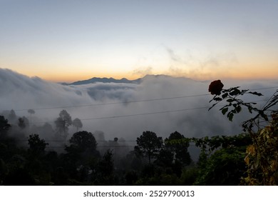 Before sunrise view, painted sky with soft orange light in the horizon. Dense clouds covers the valley and mountains in background above the clouds. Magical morning scene in mountain village in India. - Powered by Shutterstock