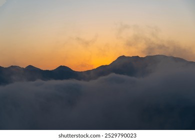 Before sunrise view, painted sky with soft orange light in the horizon. Dense clouds covers the valley and mountains in background above the clouds. Magical morning scene in mountain village in India. - Powered by Shutterstock