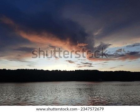 Before sunset almost gone of the day trees behind getting dark by shadow of the light from sun end up of the day to appear with amazing evening sky like strom cover with clouds navy and orange color