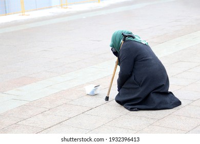 Beggar old woman asks for alms sitting on a city street. Poverty, homeless and begging concept