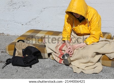 beggar sitting on a filthy mattress in the street asking for charity and alms