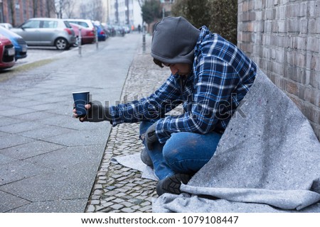 Beggar's Hand Wearing Gloves Holding Disposable Cup