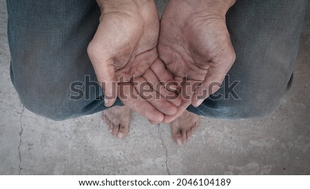 Begging. Outstretched hands. Barefoot. A homeless person. Diminution of money. Poor man. A beggar in the transition. An unemployed citizen. There is no work. Dirty hands and feet. Stink and dirt.