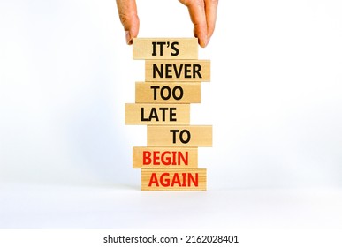 Begin again symbol. Wooden blocks with words 'It is never too late to begin again'. Businessman hand. Beautiful white background, copy space. Business and It is never too late to begin again concept.