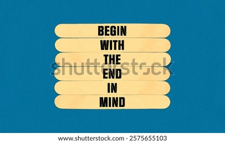 Begin in End of Mind Symbol. Concept word Begin With The End In Mind on beautiful wooden stick. Beautiful Blue Chart Paper Background. Business and Begin in End of Mind concept. Copy space