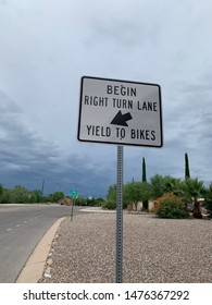 Begin Right Turn Lane, Yield To Bikes Sign Along Street