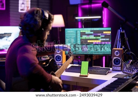 Beginner artist learning strings accords to play guitar by watching tutorials and online lessons, smartphone shows greenscreen mockup. Singer practicing acoustic instrument skills in home studio.