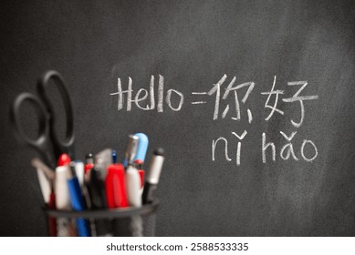 Beginner Chinese language learner writing Hello word Nihao in Chinese characters and pinyin on a chalkboard, concept of learning mandarin