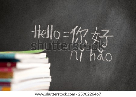 Beginner Chinese language learner writing Hello word Nihao in Chinese characters and pinyin on a chalkboard, concept of learning mandarin