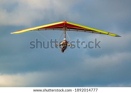 Beginner girl pilot withcolorful hang glider wing. Learning hang gliding. Extreme sports activity