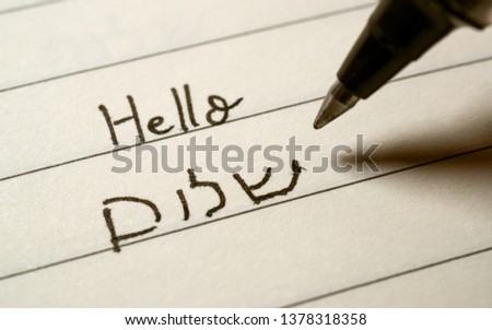 Beginner Hebrew language learner writing Hello shalom word in Hebrew alphabet on a notebook close-up shot