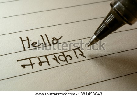 Beginner Hindi language learner writing Hello Namaste word in Indian Hindi alphabet on a notebook close-up shot