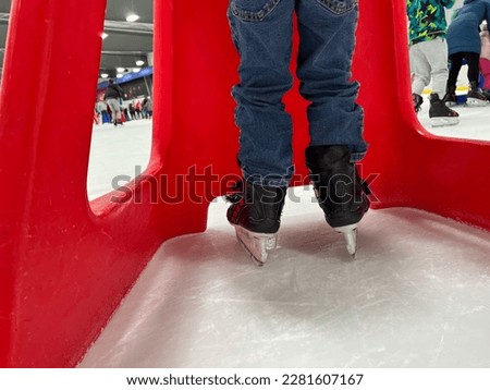 Beginner ice skater using a plastic walker for assistance.