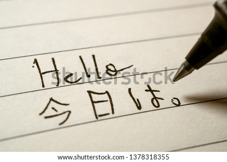 Beginner Japanese language learner writing Hello word in Japanese kanji characters on a notebook close-up shot