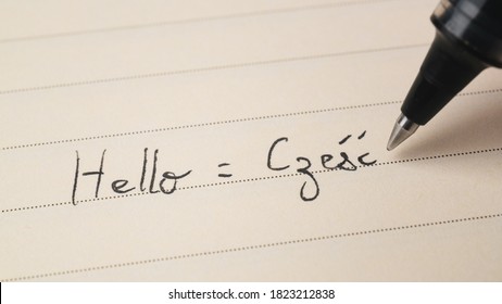 Beginner Polish language learner writing Hello word Czesc for homework on a notebook macro shot