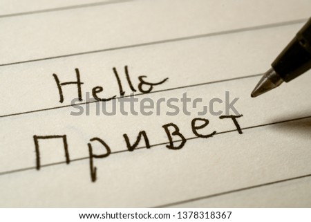 Beginner Russian language learner writing Hello word in Russian cyrillic alphabet on a notebook close-up shot