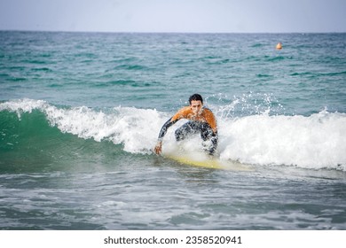 Beginner Surfer Trying to Catch a Wave and Ride But Can't Get Up on his Board and Water Foam Splashes All Over His Face