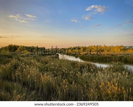 the beginning of the autumn. Autumn landscape with a flowing blue river, yellow trees on the banks and purple clouds on the blue sky. Ilek river, Aktobe, Kazakhstan