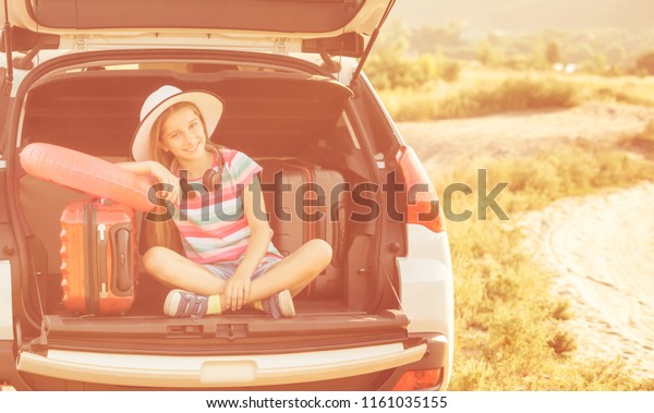 beginning of the trip. Little cute girl in the\
trunk of a car with\
suitcases