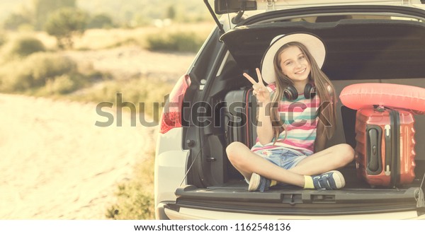 beginning of the trip. Little cute girl in the\
trunk of a car with\
suitcases