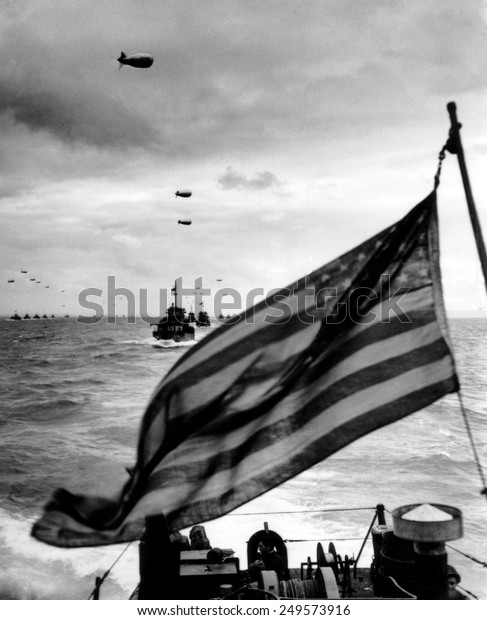 Behind an American flag, a convoy of landing craft
head for Utah Beach on June 6, 1944. Each ship has barrage balloon
connected by a cable during the D-Day invasion of Normandy on June
6, 1944.