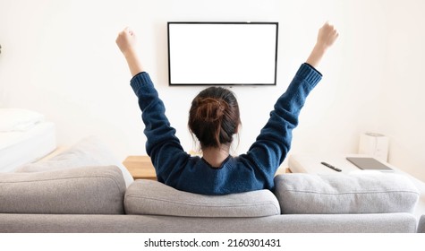 Behind Of Asian Young Woman Watching White Screen TV With Victory On Sofa At Living Room Home  At Home
