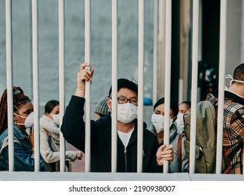 Behind Bars, Lockdown And Covid Restrictions With A Man Wearing A Mask During A Pandemic And Travel Ban. Portrait Of A Male Being Locked Out During The International Or Global Corona Virus Outbreak