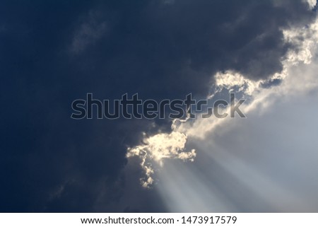 from behind the clouds the rays of the setting sun break through. Concept - God's blessing