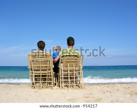 behind family on easychairs on beach