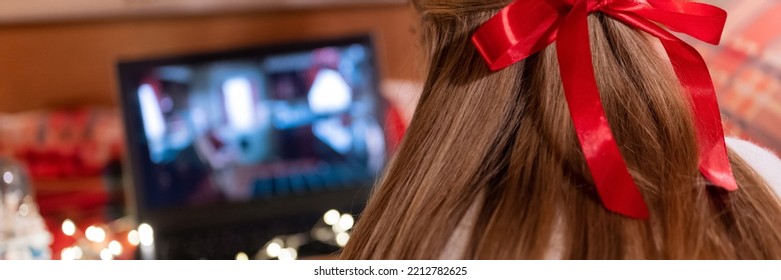 Behind Female Head Long Blondie Hair And Red Bow Rear View Watching The Christmas Movie On Laptop At Camping Home In Cozy Bed With Glowing Lights Garland At Night On Christmas Or New Year Eve. Banner