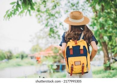 Behind The Female Tourist Carrying A Yellow Bag.