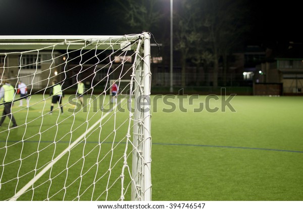 Behind Football Goalposts During Amateur Game On\
Floodlit Pitch