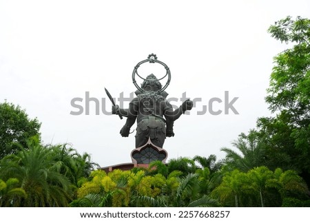 Behind Ganesh or Ganesha bronze statue, The Lord of Success  that  standing statue enshrined in the gardening park with tree and white background in Hinduism temple, Chachoengsao ,Thailand 