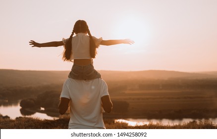 From Behind Joyful Man And Girl Spending Time Together While Having Shoulder Ride On Sunset