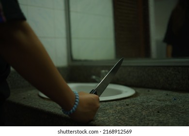 Behind The Murder Woman Holding A Knife And Looking In The Mirror In The Bathroom.Scary Horror Or Thriller Movie Mood Or Nightmare At Night Murder Or Homicide Concept.