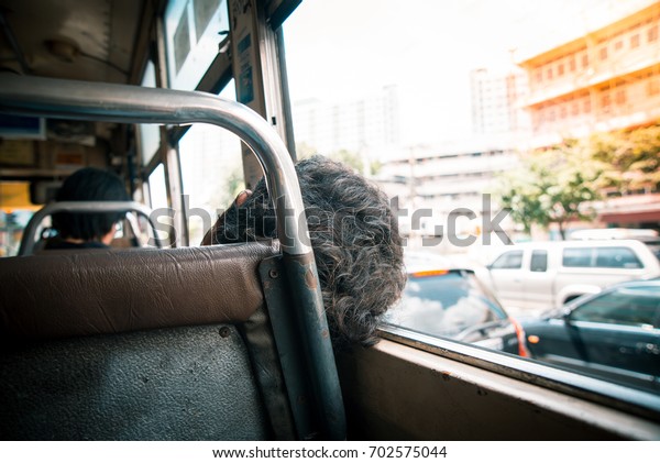 Behind the old woman\
sleeping on a bus