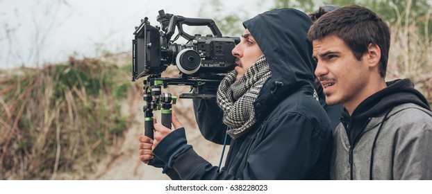 Behind the scene. Cameraman and film director shooting film scene on outdoor location