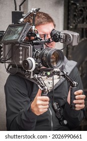 Behind The Scene. Cameraman Shooting The Film Scene With His Camera On Outdoor Set. Photography Director In Movie Filmmaking Action