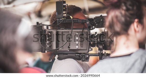 Behind the scene. Cameraman shooting the film
scene with his camera on outdoor set. Photography director in movie
filmmaking action