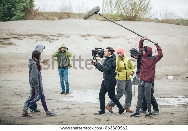 Behind the scene. Film crew team filming\
movie scene on outdoor location. Group cinema\
set