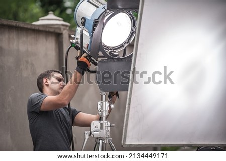 Behind the scene. Filmmaking lighting technician electric engineer adjusting and setup lights for movie film scene. Light Department. Film Crew