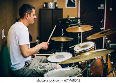 Behind the scene. Male drummer artist musician playing the drums with drumsticks in messy recording music studio. Live music - Powered by Shutterstock