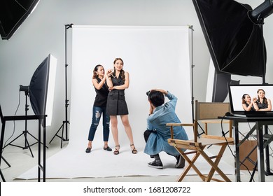 behind the scene of Professional photo shooting at the studio: a beautiful young asian model is smiling and posing with makeup artist is makeup photographer is taking pictures with a digital camera - Shutterstock ID 1681208722