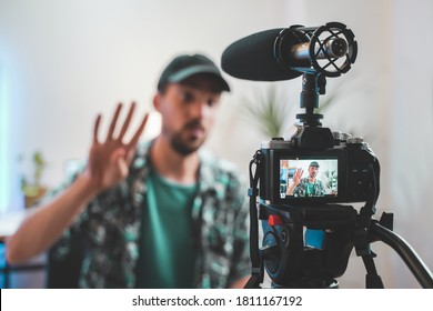 Behind the scene shot of a young man influencer making a video. Very handsome man with beard shooting a video for social media talking directly to the camera. Influencer's amazing work space.
