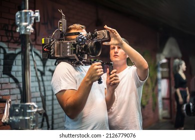 Behind The Scenes. Cameraman Shooting The Film Scene With His Camera On Outdoor Set. Photography Director In Movie Filmmaking Action