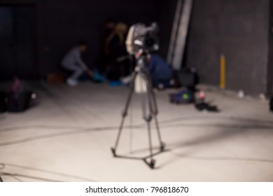 Behind the scenes or making of film in the studio and silhouette of cameraman, blurred image. blur image of group of stage staff for background usage. Video camera is ready to record.