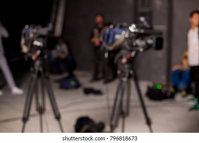 Behind the scenes or making of film in the studio and silhouette of cameraman, blurred image. blur image of group of stage staff for background usage. Video camera is ready to record.