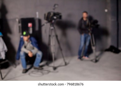 Behind the scenes or making of film in the studio and silhouette of cameraman, blurred image. blur image of group of stage staff for background usage. Video camera is ready to record.