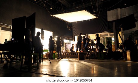 Behind the scenes or the making of film video production and movie crew team working in silhouette of camera and equipment set in studio. 
