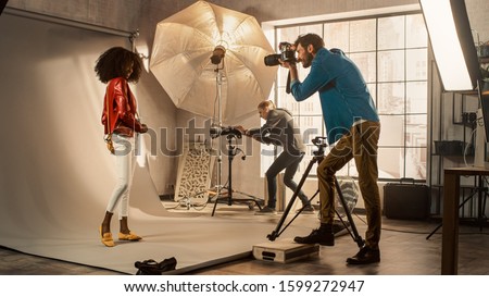 Behind the Scenes on Photo Shoot: Beautiful Black Model Posing for a Photographer, he Takes Photos with Professional Camera. Stylish Fashion Magazine Photoshoot with Pro Equipment in a Studio